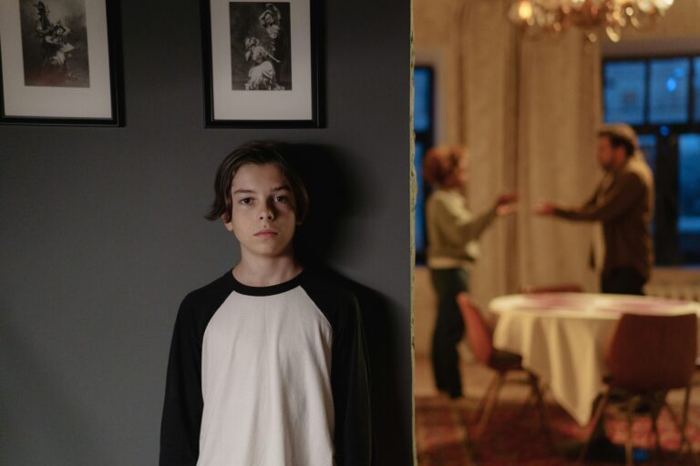 Child looking at the camera while parents argue in the background, highlighting the impact of triangulation and conflict on children during high-conflict divorce.