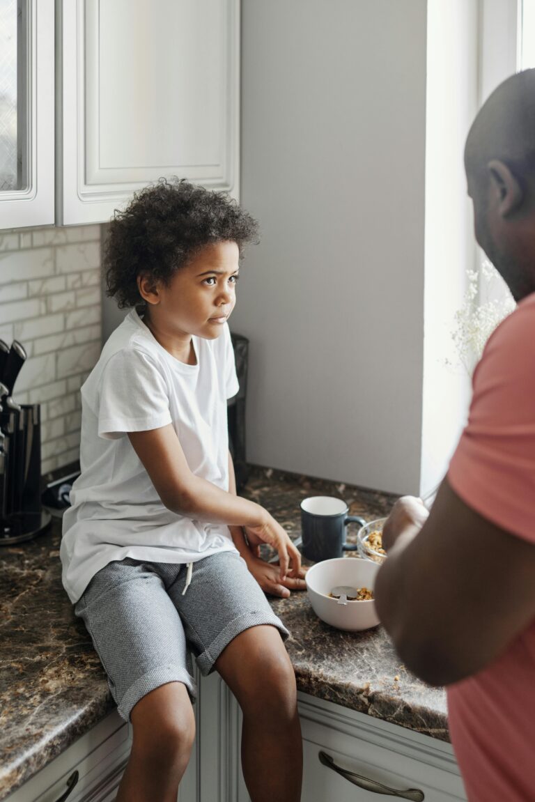 A father and son share a moment at the kitchen counter during breakfast.